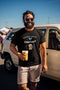 Das T-Shirt in der Farbe Schwarz trägt den Spruch "Mein erstes Wort war Durst. Das lustige Spruchshirt zeigt einen Schnuller und einen Bierkrug